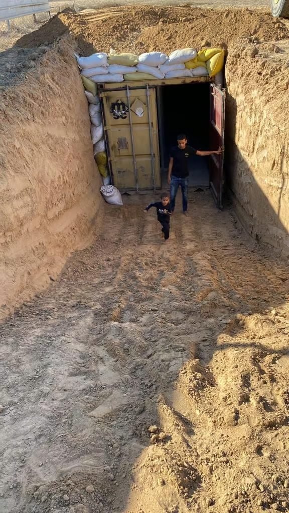 A buried container shelter in the Negev, protected by sandbags, with two children at its entrance